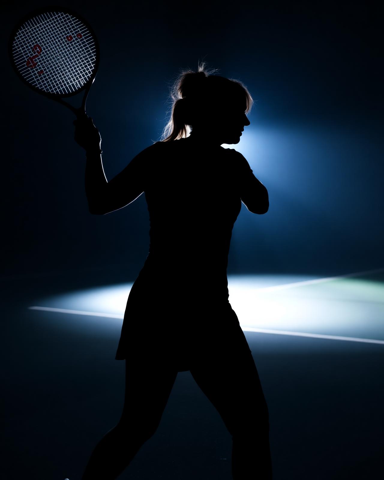 Silhouette of Lindsey mid-swing on court